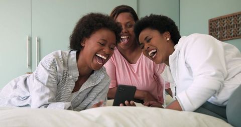 Candid Laughter with Friends Relaxing on Bed
