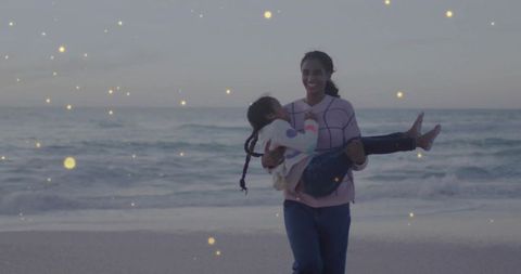 Mother Carrying Daughter on Dusk Beach Walk with Glowing Lights