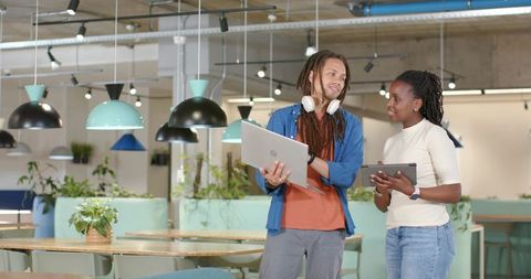 African American coworkers collaborating with laptop and tablet in modern coworking space