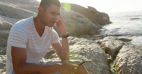 Man Contemplating on Beach Holding Mobile Phone