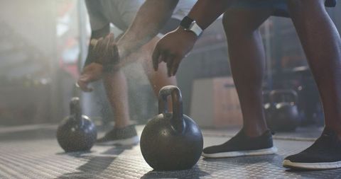 African men chalking hands gripping kettlebells preparing strength training session