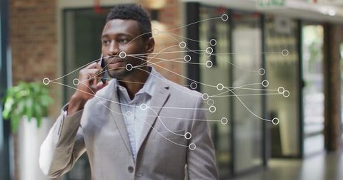 Businessman Walking in Office Corridor Using Smartphone