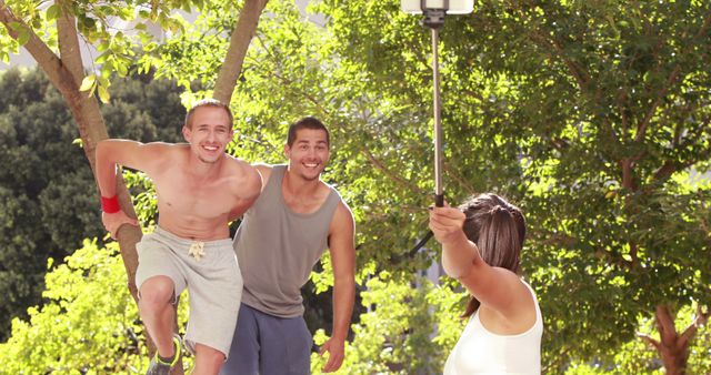 Two young men enjoy a playful moment on a swing outdoors, with a woman capturing the fun on her camera, with copy space. Their laughter and camaraderie under the sun create a snapshot of joyful summer days.