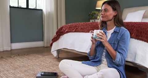 Woman Enjoying Coffee in Cozy Bedroom Setting