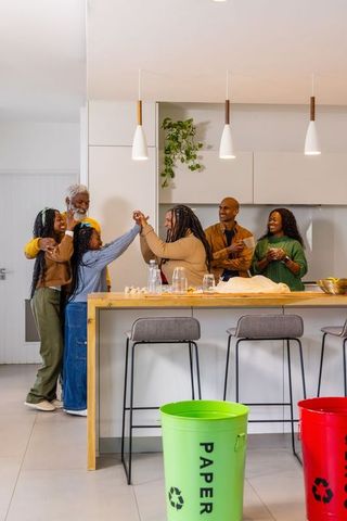 African american multigenerational family celebrating at kitchen island with recycling bins