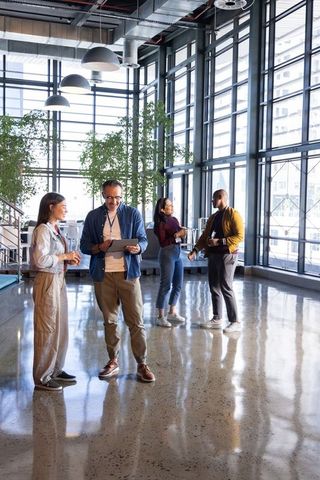 Diverse team collaborating in modern glass atrium for business networking and discussion