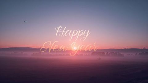 Happy new year glowing cursive greeting over pastel misty dawn fields with golden sunrise