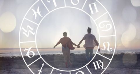 Happy Couple Holding Hands with Overlay of Zodiac Symbols on Beach
