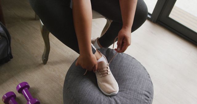 Image of legs of plus size african american woman in sport clothes tying shoes. active healthy lifestyle, exercising at home.