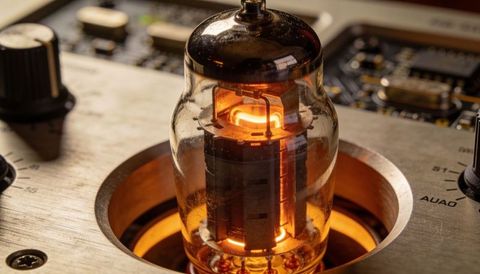 Glowing vacuum tube in tube amplifier chassis, warm thermionic filament illuminating pcb