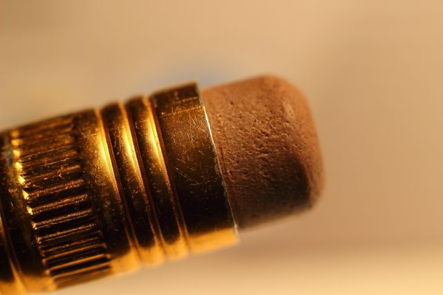 This macro close-up highlights the intricate details of a pencil's eraser and golden ferrule. Perfect for articles or advertisements related to stationery, education, office supplies, and back-to-school themes.