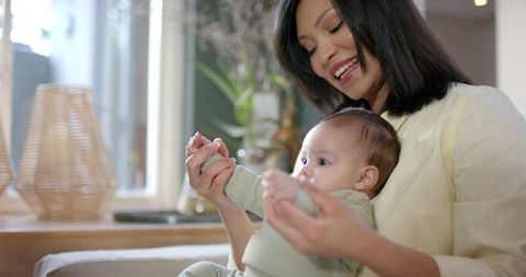 Mother Bonding While Holding Infant Daughter Indoors with Warm Lighting
