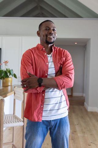 African american man smiling and standing in bright modern kitchen with vaulted ceiling