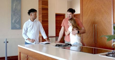 Couple Consulting With Real Estate Agent In Modern Kitchen