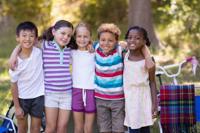 Diverse group of children standing close together outdoors, smiling and enjoying their time at a campsite. Ideal for use in advertisements, educational materials, or articles about childhood, friendship, outdoor activities, and summer vacations.
