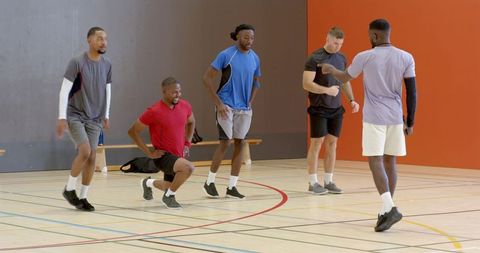 Men warming up on indoor gym court for group training session demonstrating teamwork and fitness
