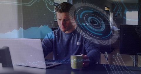 Young developer coding on laptop with futuristic HUD overlays holding green mug