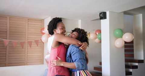 Female couple hugging with colorful birthday decorations
