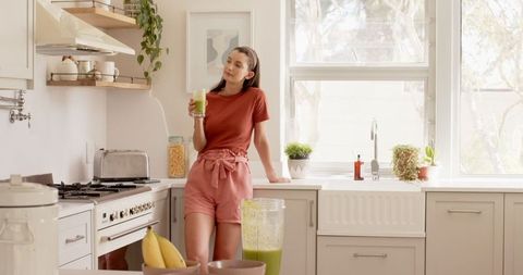 Woman Enjoys Healthy Green Smoothie in Bright Kitchen