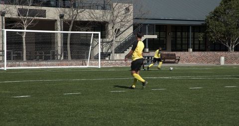 Soccer Players in Yellow Jerseys Practicing on Green Field