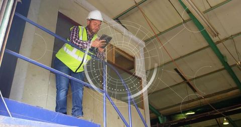 Construction supervisor inspecting warehouse mezzanine with tablet and safety gear