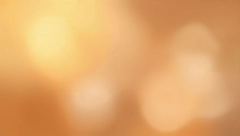 Glowing peach bokeh backdrop with golden orbs and soft warm light gradient for designs