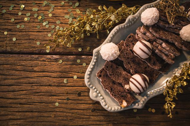 Festive Christmas desserts arranged on a rustic wooden table, featuring chocolate truffles and decorative elements. Ideal for holiday-themed promotions, food blogs, festive greeting cards, and seasonal marketing materials.