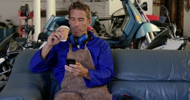 Mechanic Taking a Coffee Break While Checking Smartphone - Download Free Stock Images Pikwizard.com