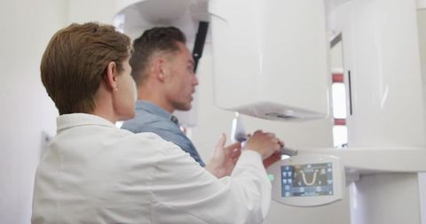 Dental technician aligning patient for panoramic x-ray with bite spacer and head strap