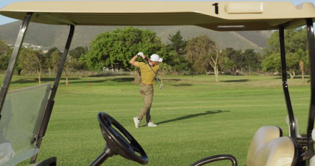 Golf cart over aucasian male golf player playing golf at golf course. Golf, sport and active lifestyle, unaltered.