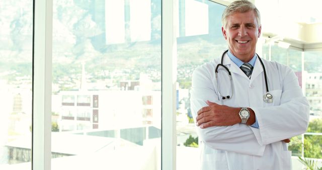 Confident Senior Doctor Standing with Arms Crossed in Modern Hospital - Download Free Stock Images Pikwizard.com