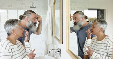 Senior Couple Examining Faces in Bathroom Mirror
