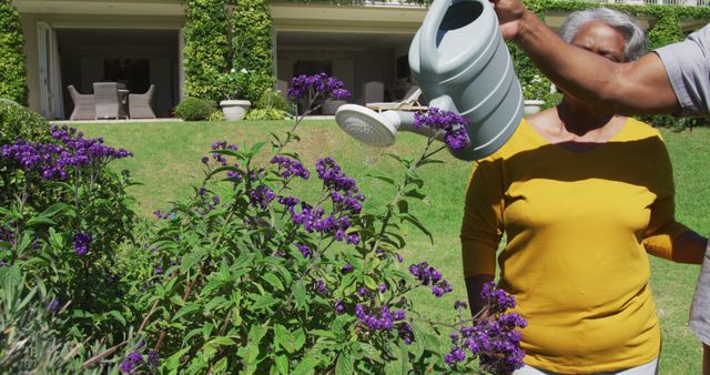 African american senior man smiling while watering plants in the garden - Download Free Stock Photos Pikwizard.com