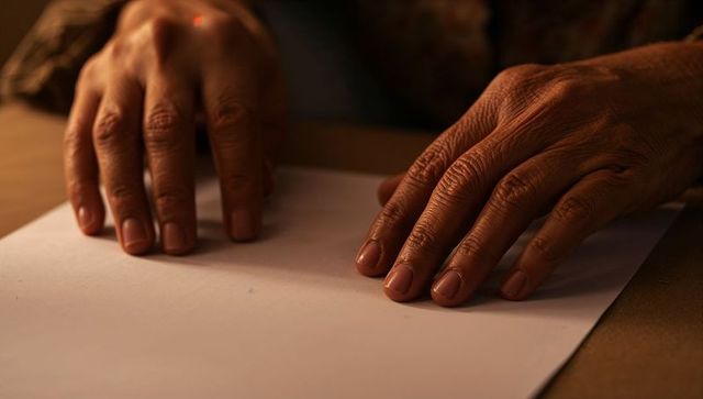 Senior hands placing palms on blank paper showing wrinkles, texture and patterned cuff