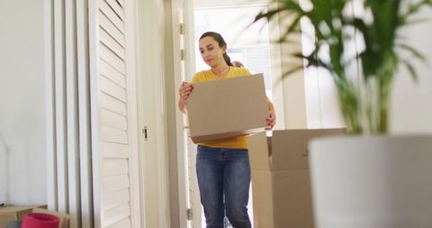 Young Couple Moving Into New Home Holding Boxes