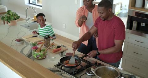 African american family cooking together on marble kitchen island preparing healthy dinner