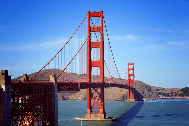 Golden Gate Bridge with clear blue sky and calm waters. Ideal for travel and tourism websites, promotional materials, postcards, or educational content highlighting significant landmarks and architectural feats.