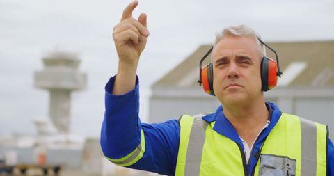 Male airport worker directing aircraft in daylight