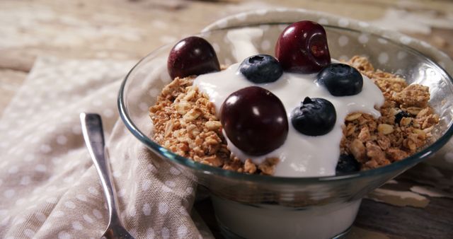 Bowl of yogurt muesli, cherries and blueberries for breakfast on a wooden table 4k
