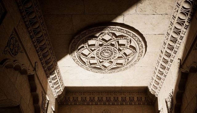 Sunlit ornate rosette ceiling medallion in historic stone hall with strong diagonal shadow