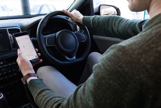 Man looking at map in smartphone while driving car