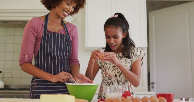 This heartwarming image showing an African American mother and daughter baking together can be used in campaigns focused on family bonding, parenting articles, cooking blogs, and advertisements promoting homeware or kitchen products. It depicts love, unity, and joyful domestic life.