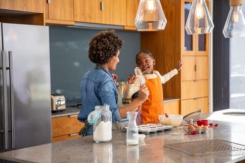 African American Mother and Daughter Whisking Batter Together at Home