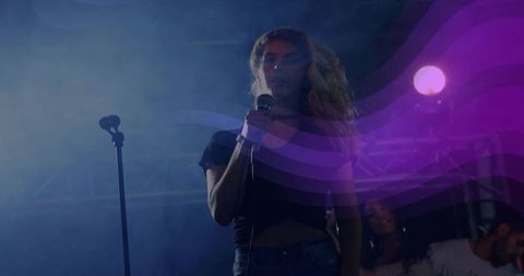 Female Singer Performing Under Purple Stage Lights Holding Wired Microphone