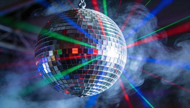 Mirrored disco ball throwing multicolor laser beams through fog for party energy