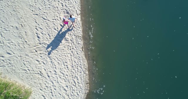 Aerial View of Couple Walking Along Sandy Beach Shoreline - Download Free Stock Images Pikwizard.com