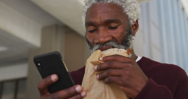 Senior Man Eating Sandwich and Using Smartphone Outdoors - Download Free Stock Images Pikwizard.com