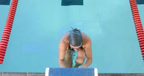 Female swimmer preparing on starting block in competition pool with red lane ropes