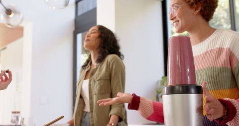 Diverse friends socializing while blending smoothie in kitchen
