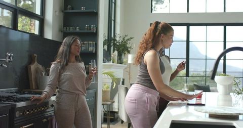African american women chatting in kitchen wearing loungewear and pink joggers